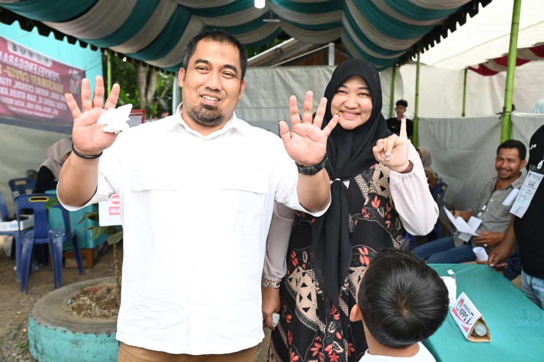 Pj Bupati Aceh Besar Muhammad Iswanto SSTP MM bersama Istri menunjukkan jari tanda sudah menggunakan hak pilih atau mencoblos di TPS 01, di halaman Masjid Gampong Gani, Kecamatan Ingin Jaya, Aceh Besar, Rabu (14/2/2024).